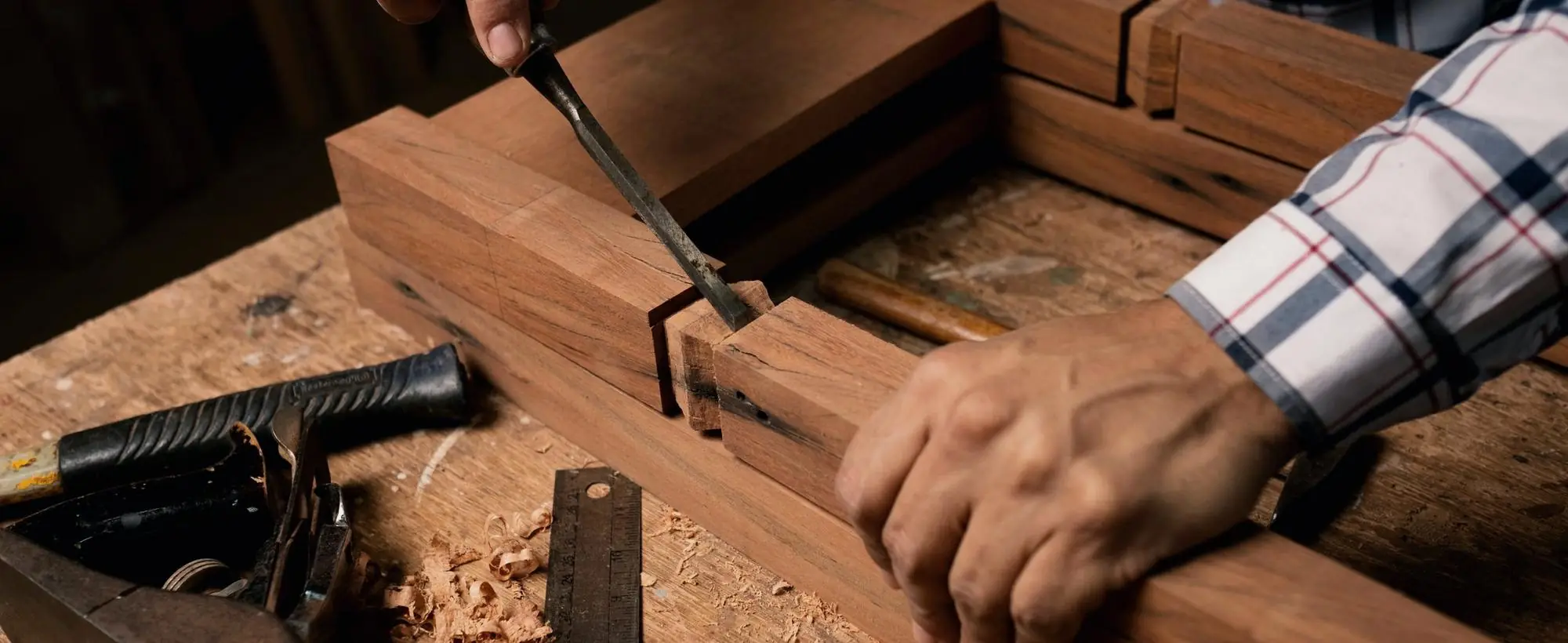 Mains d’un artisan travaillant le bois au ciseau